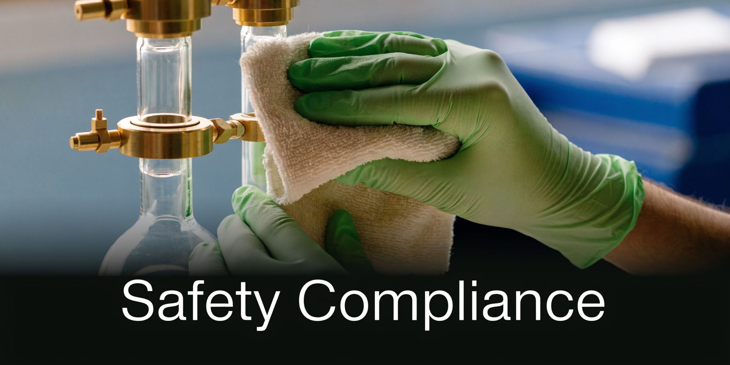 A gloved hand cleaning lab glassware with a white cloth to ensure safety compliance in the laboratory.