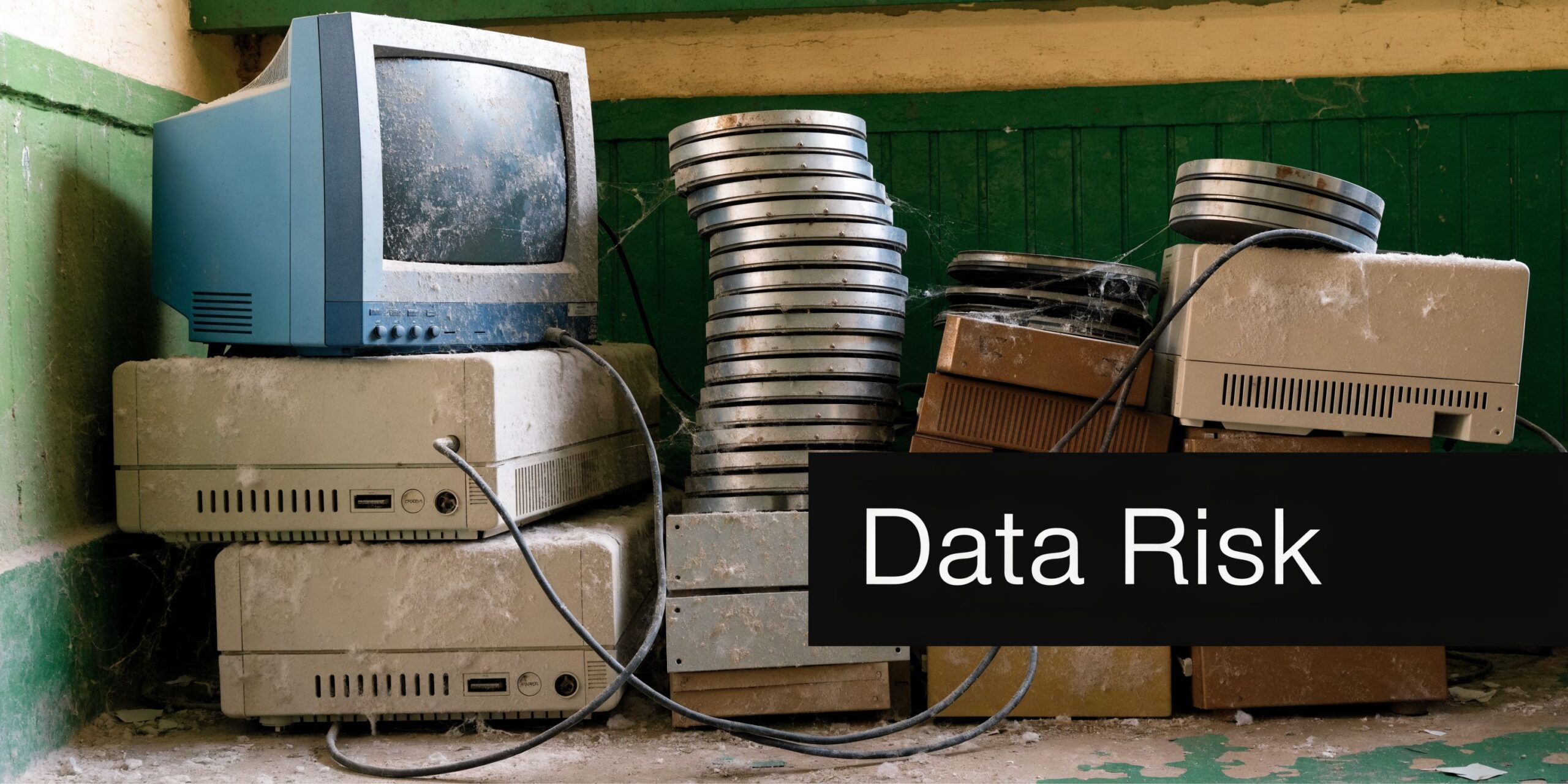 A stack of old, dusty computer monitors and electronic hardware left in an abandoned room with wires.